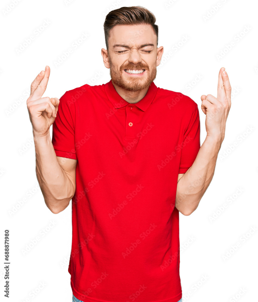 Naklejka premium Young redhead man wearing casual clothes gesturing finger crossed smiling with hope and eyes closed. luck and superstitious concept.