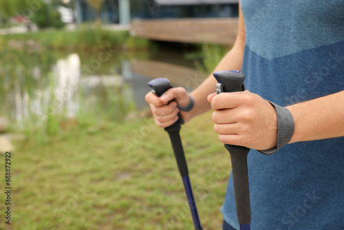 Man practicing Nordic walking with poles outdoors, closeup. Space for text