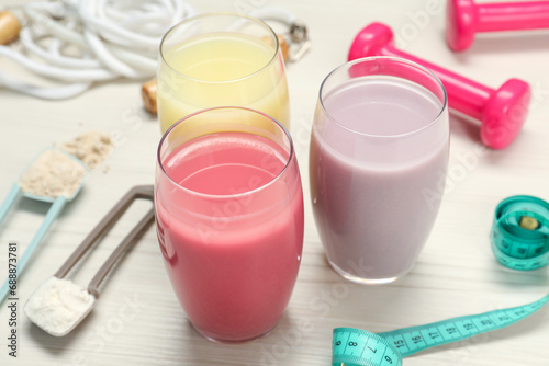 Tasty shakes, sports equipment, measuring tape and different powders on wooden table, closeup. Weight loss