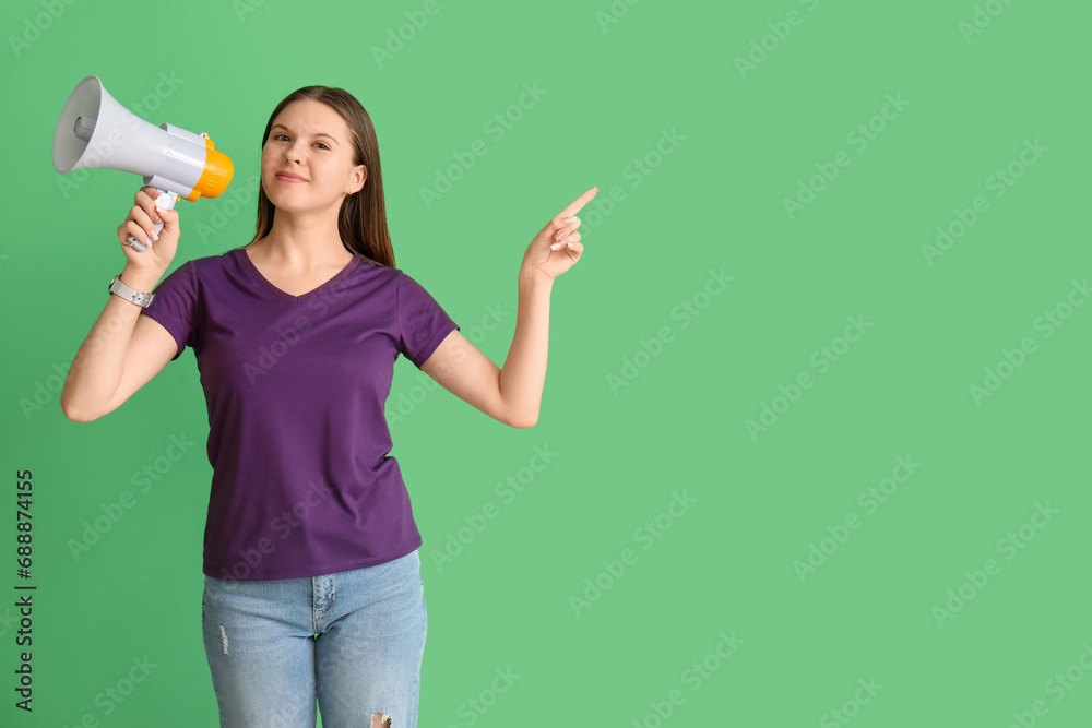Young woman with megaphone pointing at something on green background Young woman with megaphone pointing at something on green background