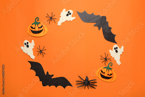 Frame made of cardboard bats, felt pumpkins, ghosts and spiders on orange background, space for text. Halloween celebration