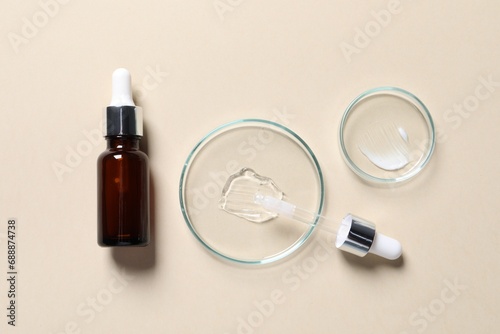 Bottle of cosmetic serum and petri dishes with samples on beige background, flat lay