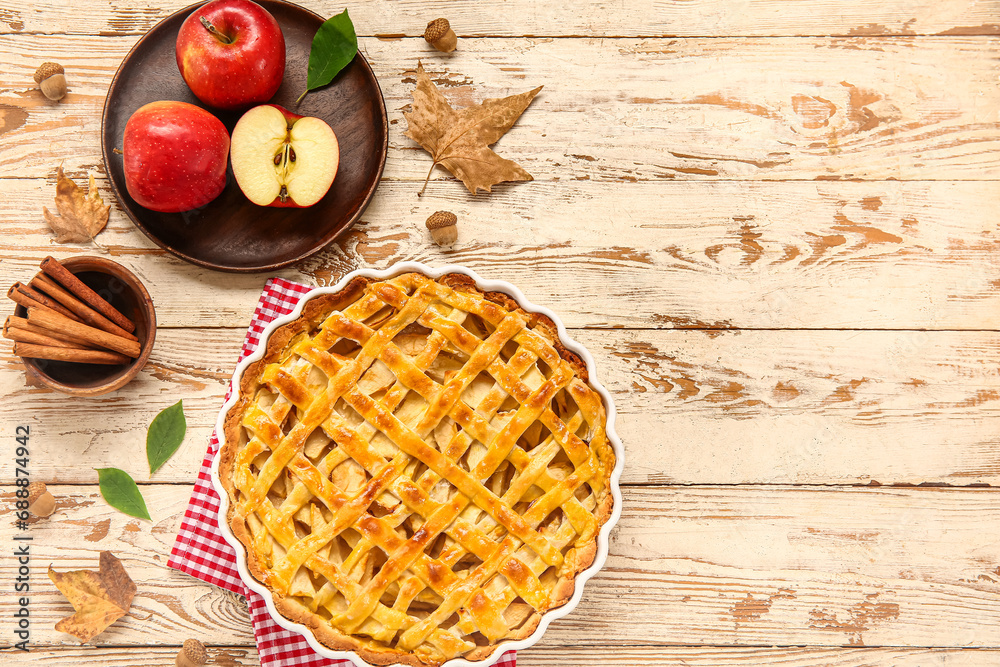 Baking dish with delicious apple pie and bowl of cinnamon on white wooden background Baking dish with delicious apple pie and bowl of cinnamon on white wooden background
