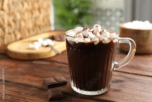 Cup of aromatic hot chocolate with marshmallows and cocoa powder on wooden table, closeup. Space for text