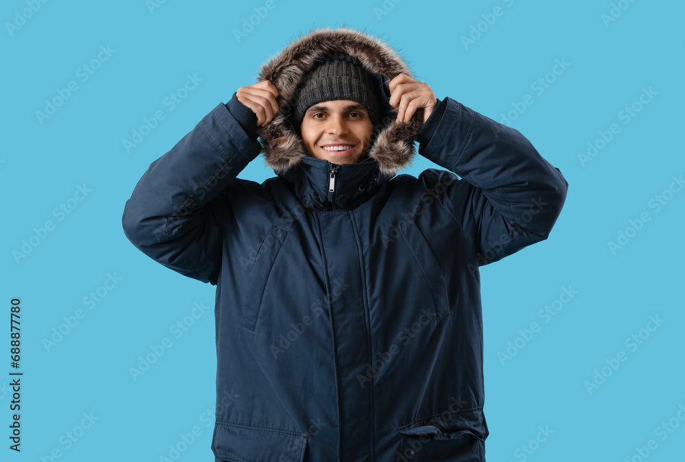 Young man in warm parka on blue background Young man in warm parka on blue background