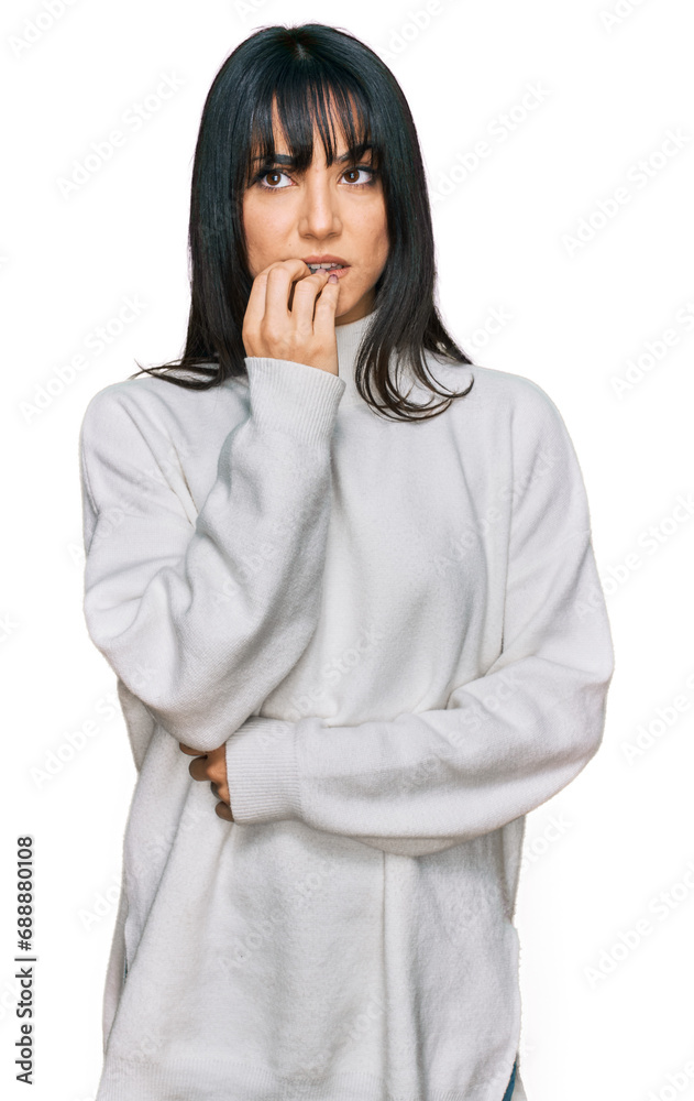 Young brunette woman with bangs wearing casual turtleneck sweater looking stressed and nervous with hands on mouth biting nails. anxiety problem. Young brunette woman with bangs wearing casual turtleneck sweater looking stressed and nervous with hands on mouth biting nails. anxiety problem.