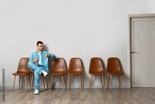 Young man with mobile phone waiting for his turn in room photo