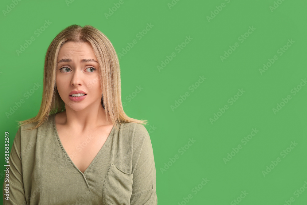 Young woman feeling embarrassment on green background Young woman feeling embarrassment on green background