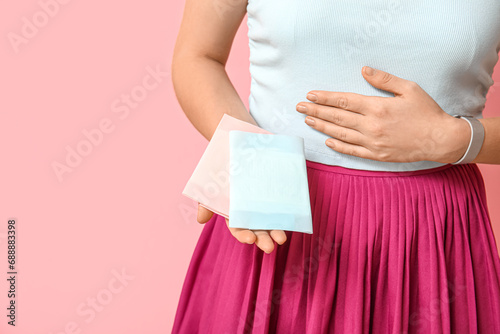 Young woman with menstrual pads on pink background, closeup photo