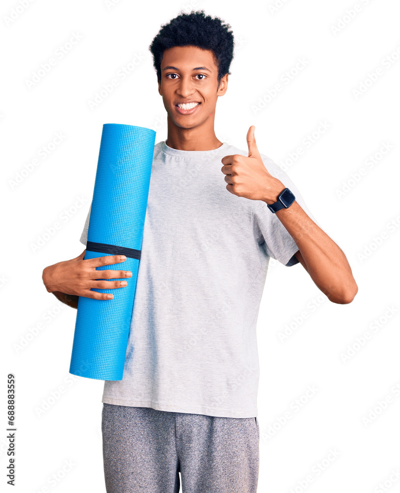 Young african american man holding yoga mat smiling happy and positive, thumb up doing excellent and approval sign Young african american man holding yoga mat smiling happy and positive, thumb up doing excellent and approval sign