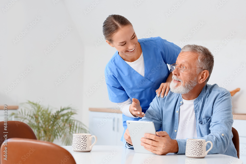 Senior man with nurse using tablet computer in kitchen Senior man with nurse using tablet computer in kitchen