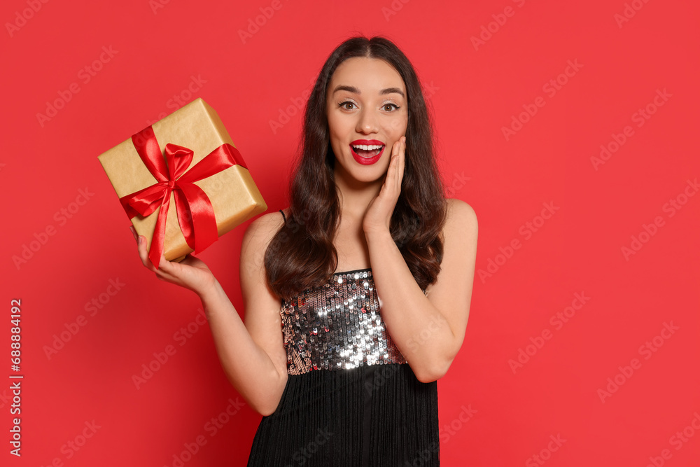 Beautiful emotional woman with Christmas gift on red background Beautiful emotional woman with Christmas gift on red background