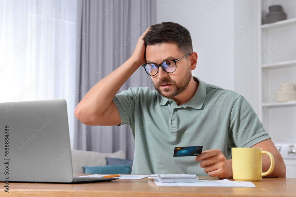 Man with credit card using laptop for paying taxes online at home Man with credit card using laptop for paying taxes online at home
