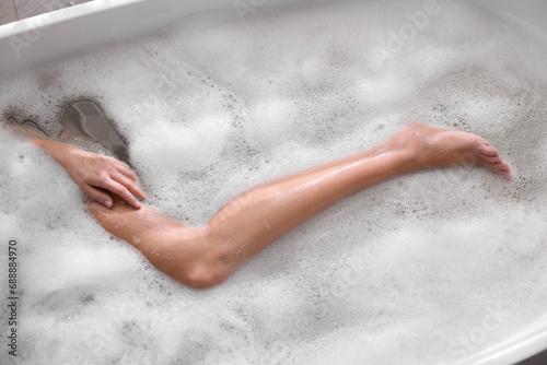 Woman taking bath in tub with foam, top view