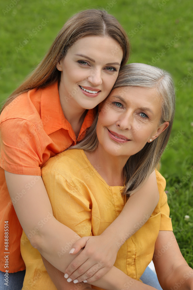 Happy mature mother and her daughter hugging outdoors