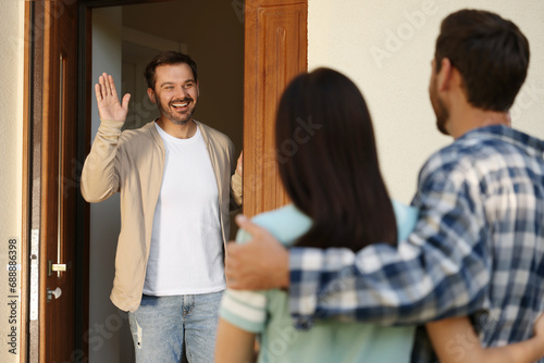 Friendly relationship with neighbours. Young couple visiting happy man photo