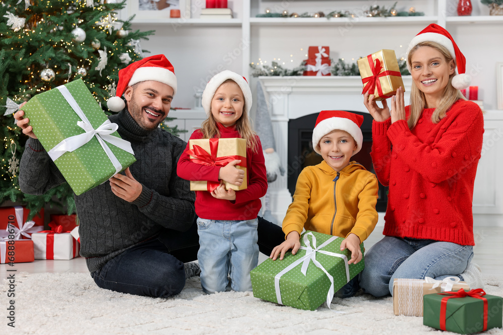 Φωτογραφία Happy family in Santa hats with Christmas gifts at home