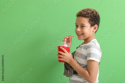 Little African-American boy with cup of cola on green background