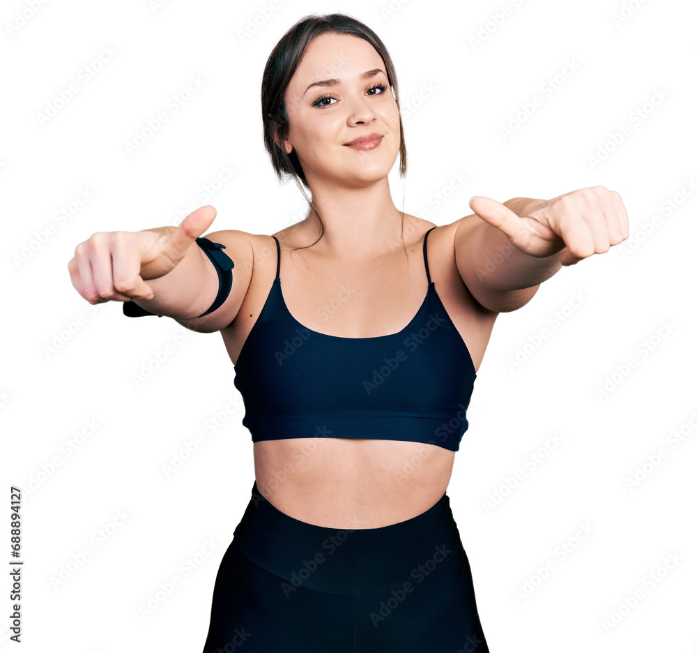 Young hispanic woman wearing sportswear approving doing positive gesture with hand, thumbs up smiling and happy for success. winner gesture. Young hispanic woman wearing sportswear approving doing positive gesture with hand, thumbs up smiling and happy for success. winner gesture.