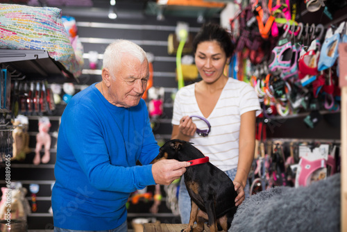 Woman helping an elderly man to choose collar for a dog