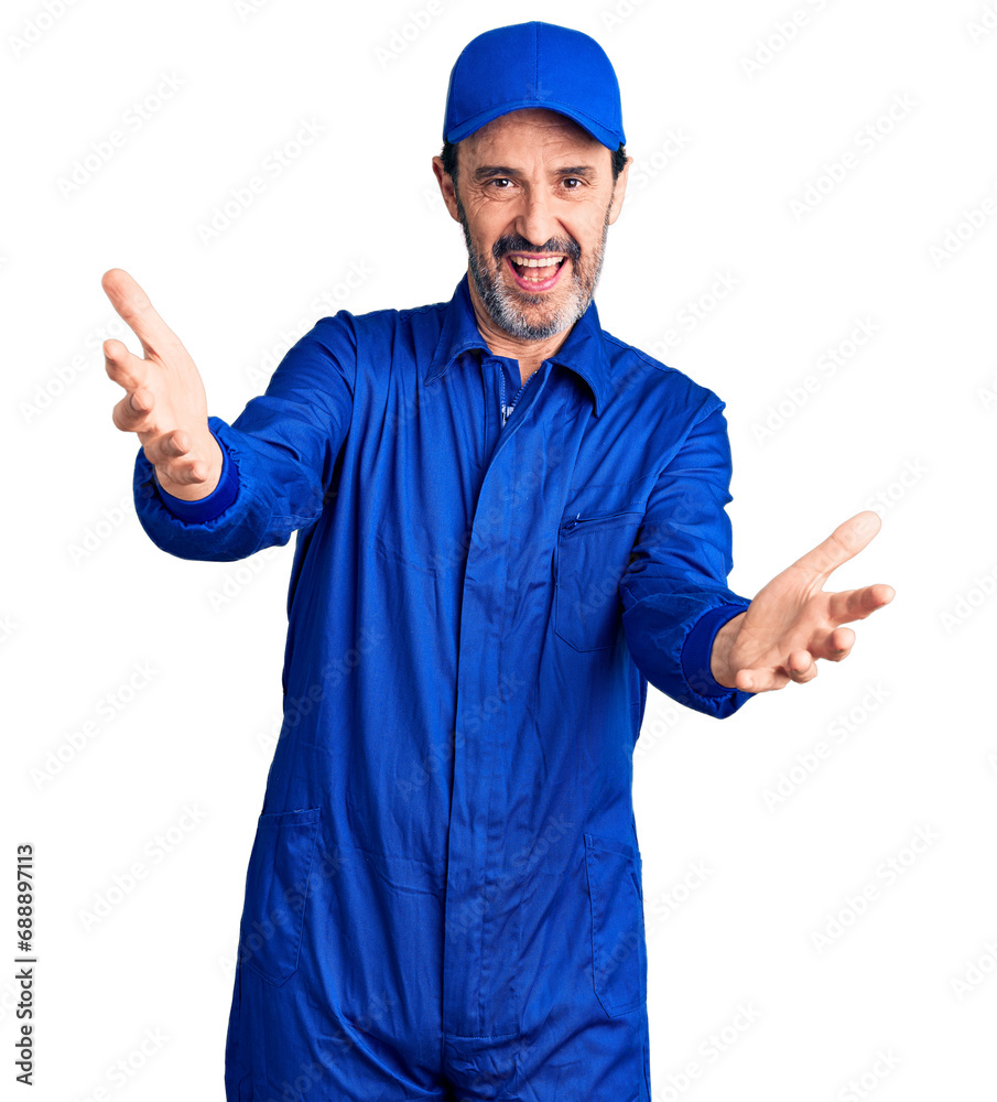 Middle age handsome man wearing mechanic uniform smiling cheerful offering hands giving assistance and acceptance.