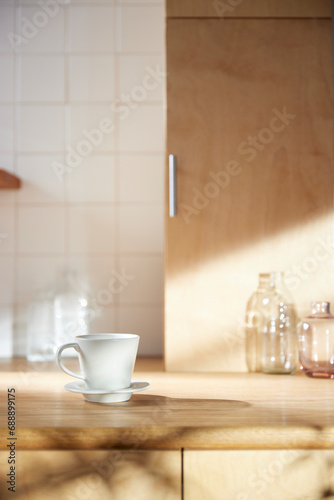 A sunny kitchen with white tile walls  a wooden table and sink.