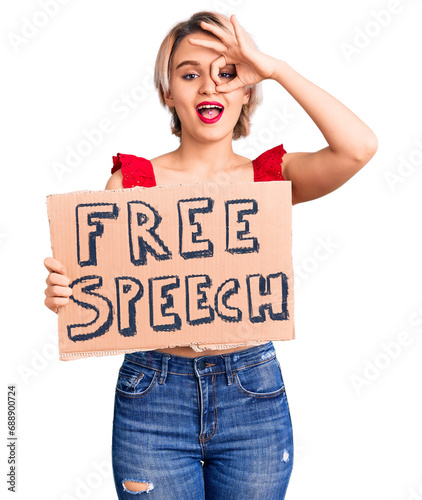 Young beautiful blonde woman holding free speech banner smiling happy doing ok sign with hand on eye looking through fingers © Krakenimages.com