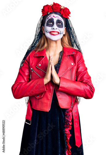 Woman wearing day of the dead costume over background begging and praying with hands together with hope expression on face very emotional and worried. begging.