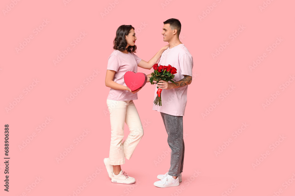 Loving young couple with gift box and bouquet of beautiful roses on pink background. Celebration of Saint Valentine's Day Loving young couple with gift box and bouquet of beautiful roses on pink background. Celebration of Saint Valentine's Day