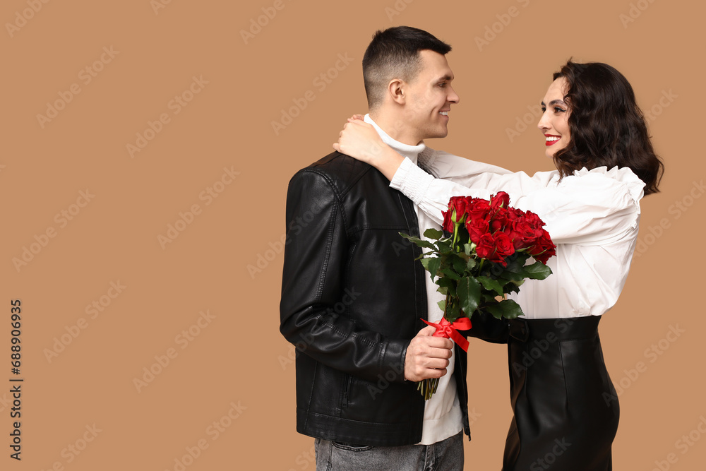 Loving young couple with bouquet of beautiful roses on brown background. Celebration of Saint Valentine's Day Loving young couple with bouquet of beautiful roses on brown background. Celebration of Saint Valentine's Day