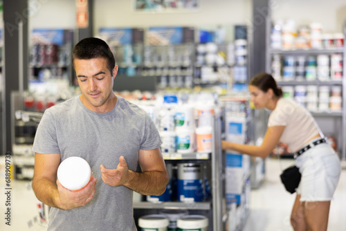 Male customer chooses can of paint in a hardware store photo