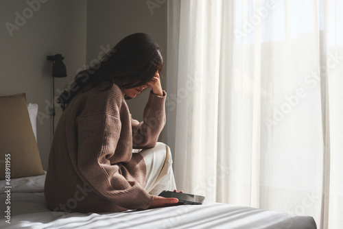 Rear view of a sad woman after reading bad news on smartphone in bedroom photo