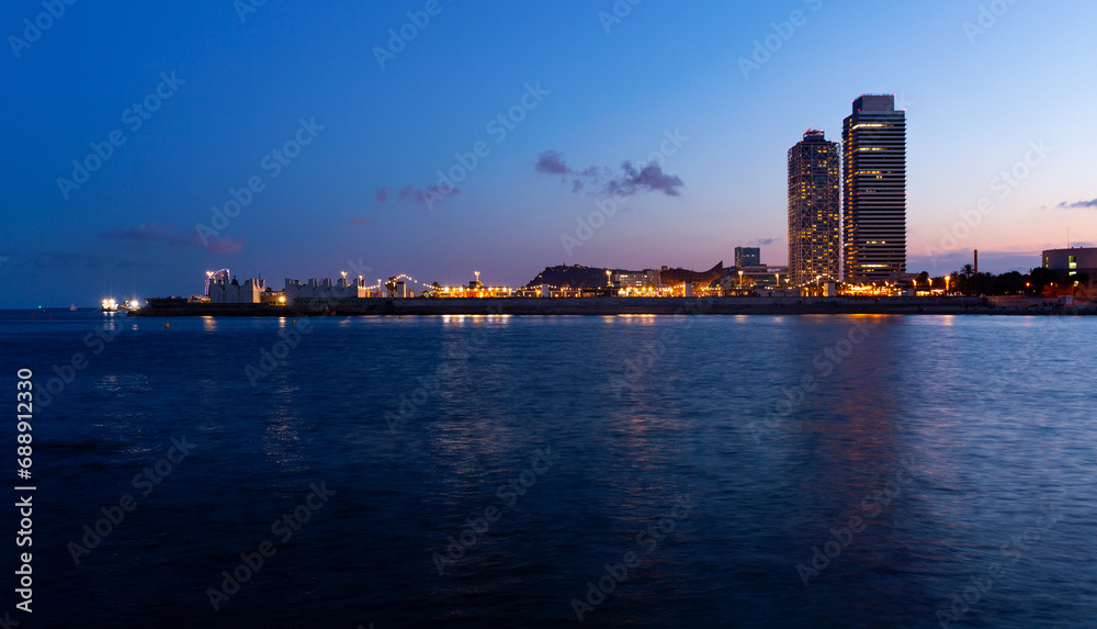 Evening view of Barcelona with illuminated buildings from Mediterranean sea