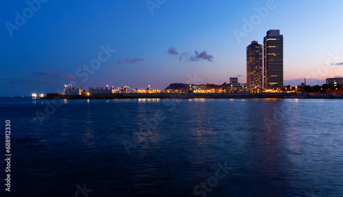Evening view of Barcelona with illuminated buildings from Mediterranean sea