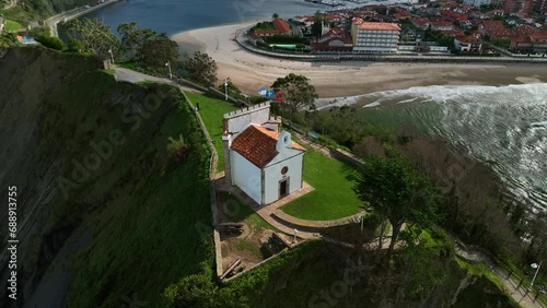 SPECTACULAR VIEWS OF THE HERMITAGE OF LA GUIA DOMINATING THE ENTRANCE TO THE COVE OF THE MYTHICAL PORT OF RIBADESELLA IN ASTURIAS photo