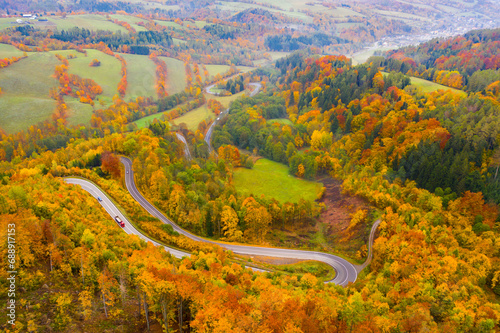 Aerial autumn rural landscape with winding road, fields and forest