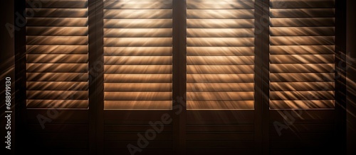 Sunlight shines through wooden shutters, lighting dust in dark room.