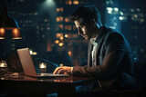 Businessman using laptop working on desk at night.