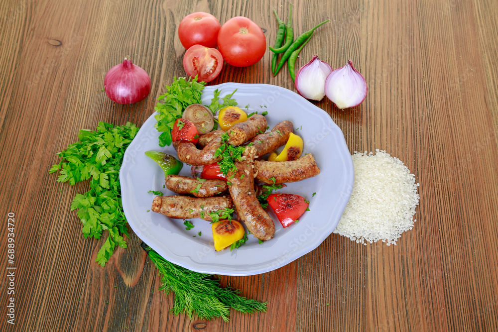 Grilled mumbar or sausage grill with onion, tomato and coriander served in dish isolated on table top view of arabic food Grilled mumbar or sausage grill with onion, tomato and coriander served in dish isolated on table top view of arabic food