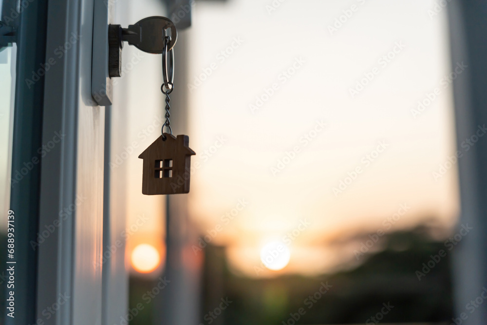 Landlord key for unlocking house is plugged into the door. Second hand house for rent and sale. keychain is blowing in the wind. mortgage for new home, buy, sell, renovate, investment, owner, estate - obrazy, fototapety, plakaty 