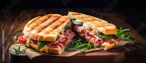 Top view of a panini with ham, cheese, tomato, and herbs, resembling a club sandwich.