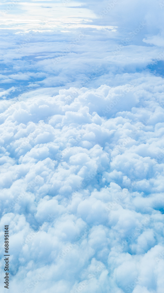 Sky blue background with white clouds, showcasing the beauty of nature. View from airplane window