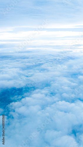 Sky blue background with white clouds, showcasing the beauty of nature. View from airplane window