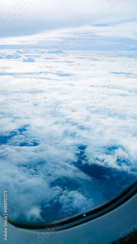Sky blue background with white clouds, showcasing the beauty of nature. View from airplane window © Tanawat Thipmontha