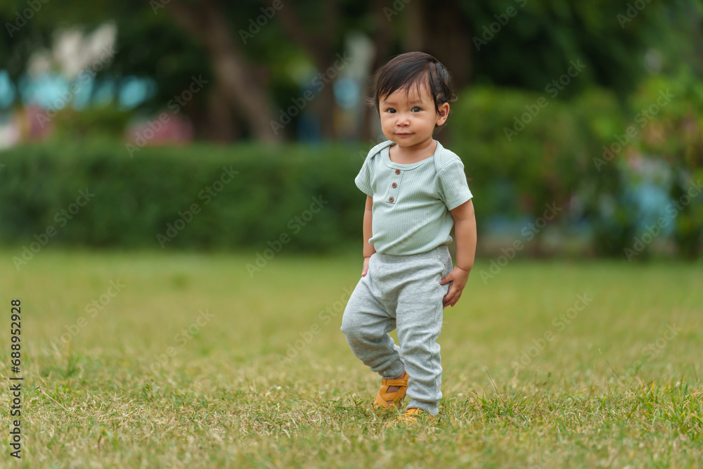 happy infant baby standing on green grass in park happy infant baby standing on green grass in park