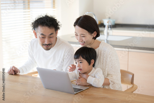 ダイニングでパソコンを使う家族 幼児教育などのイメージ