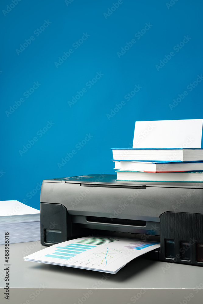 Laser printer on desk against blue background. Laser printer on desk against blue background.
