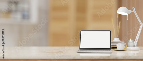 A workspace with a laptop computer mockup on a white marble tabletop over a blurred background.