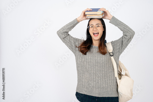 Happy adorable Asian college student with books and backpack on white isolated background.