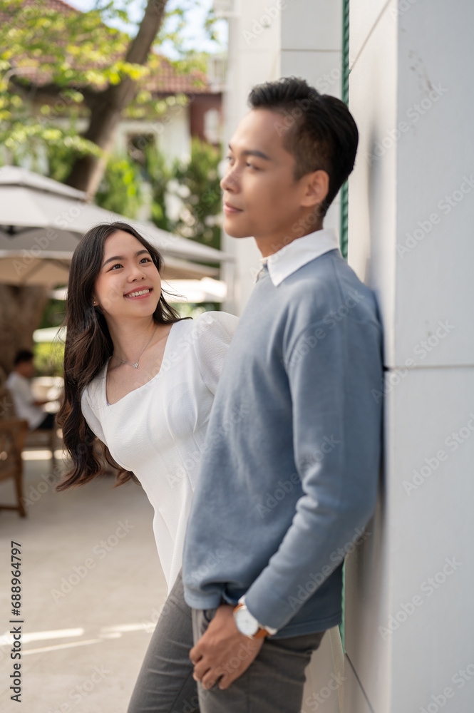 Young beautiful Asian couple standing in front of their house, having a good time together. Young beautiful Asian couple standing in front of their house, having a good time together.